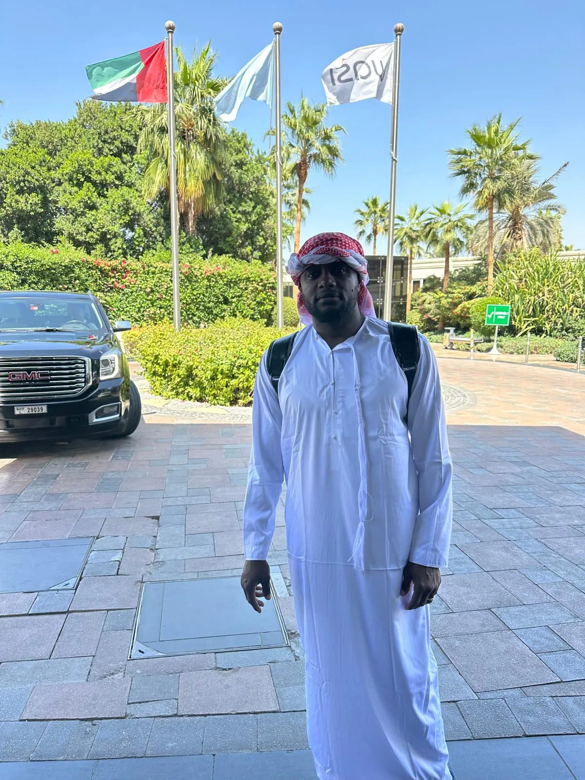 Pierre Olivier Bakalag at a Dubai location in Emirati traditional dress, UAE flag in the background.